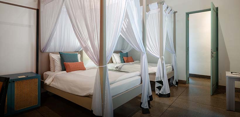 Comfortable twin canopy beds with white drapes at Walawwa, a luxury boutique hotel in Colombo. A peaceful and stylish place to relax