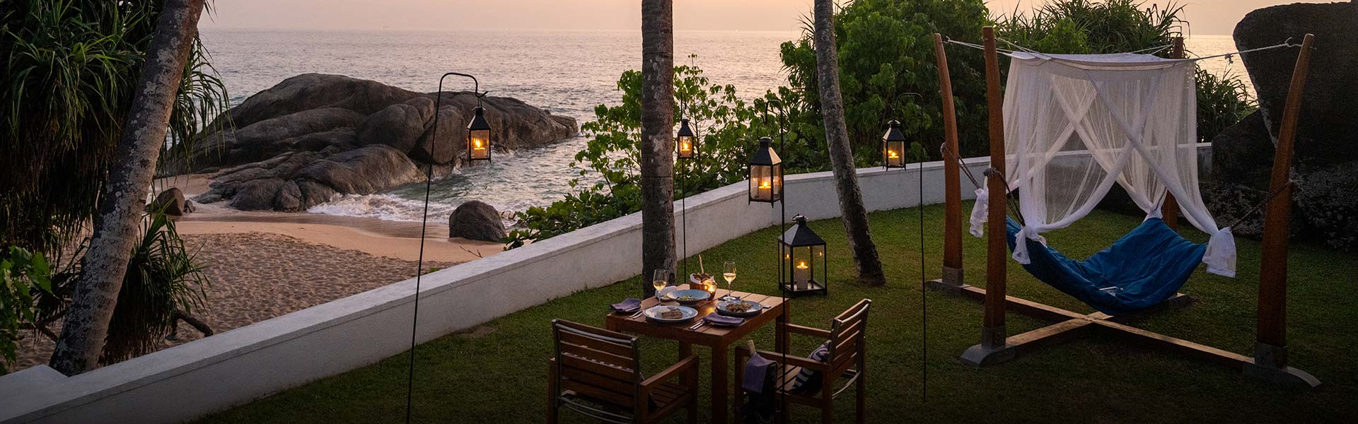 Teardrop Hotels, one of the best romantic hotels in Sri Lanka, offers romantic beachside dinner setup with a hammock and lanterns.