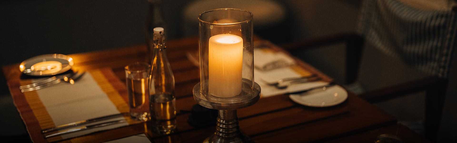 Teardrop Hotels – A romantic candlelit table setting with a tall glass candle, perfect for a honeymoon in Sri Lanka